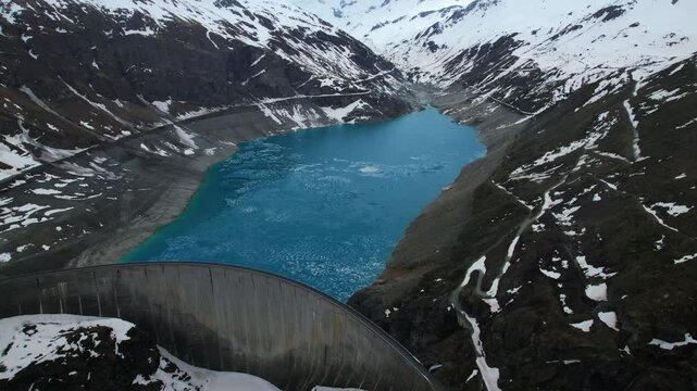 4k Drone Aerial View Of Vibrant Blue Glacial Water Of Lac de Moiry Dam Surrounded By Massive Snow Covered Mountains In Grimentz Switzerland