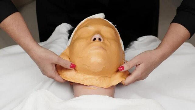 Close-up of a cosmetologist removing an alginate mask in a contemporary skincare center. This scene highlights the meticulous process and expertise involved in advanced facial treatments.