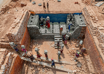 Aerial view of a dusty brick factory with workers manually producing bricks under a sunny sky, Dhaka, Bangladesh.