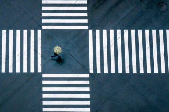 Aerial view of an empty urban street crossing with a lone man running under an umbrella, Yurakucho, Tokyo Metropolis, Japan.