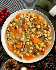 Chickpea and rice soup with mushrooms and vegetables. Top view table with Christmas decorations.