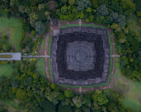 Aerial view of the ancient Borobudur temple surrounded by lush greenery at sunrise, Yogyakarta, Indonesia.