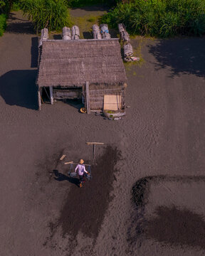 Aerial view of a scenic beach with traditional huts and salt mining activities, Karangasem, Indonesia.