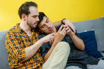 Gay couple sharing a moment with smartphone at home