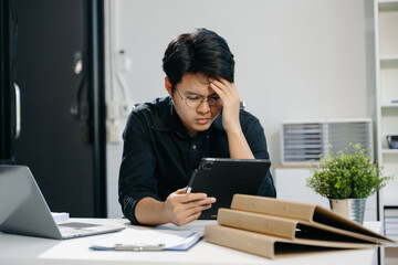 Frustrated young businessman working on a laptop computer sitting at his working place