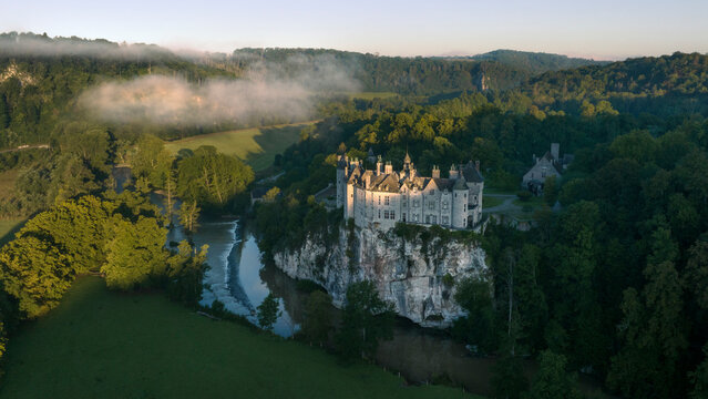 Aerial view of the medieval Walzin castle overlooking the river amidst lush greenery at sunrise, Dinant, Belgium.
