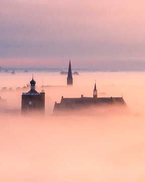 Aerial view of a beautiful city shrouded in fog with a church at sunrise, Workum, Netherlands.