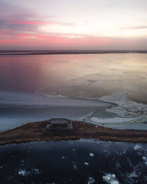 Aerial view of a frozen ijsselmeer with a war bunker at sunrise, Kornwerderzand, Netherlands.