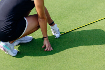 A golfer adjusts the ball position on the putting green during a sunny day at a local golf course...
