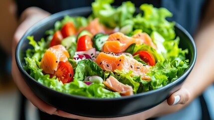 Healthy Young woman holding Salted salmon salad bowl with fresh green lettuce,smoked salmon,tomato,Ketogenic,diet lunch bowl,enjoy eat clean vegetables after exercise,Healthy food concept.