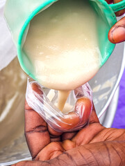 Local food vendor dishing out porridge into a rubber bag