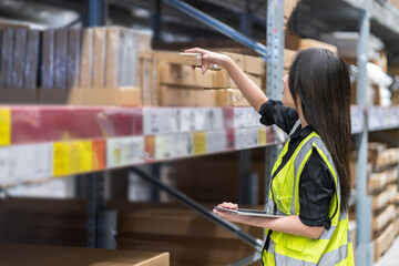 Female engineer is handling shipping and checking stock inventory in the warehouse with a tablet,...