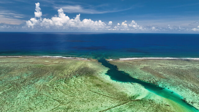 Aerial view of the serene turquoise lagoon and vibrant coral reef under a clear sky, Rarotonga, Cook Islands.