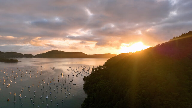 Aerial view of serene sunrise over calm sea with boats and lush mountains, Angra dos Reis, Brazil.