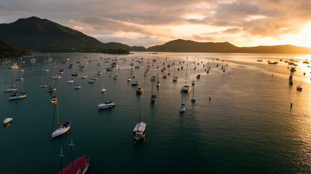 Aerial view of scenic sunset over tranquil bay with anchored boats and mountains, Angra dos Reis, Brazil.