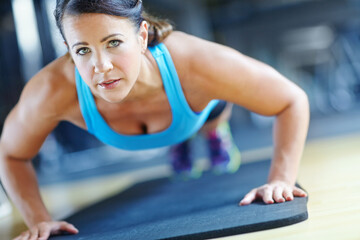 Fototapeta premium Fitness, push up and woman in gym for exercise, workout and training for performance or endurance. Sports, serious and person on floor for strong, wellness or health for strength, muscle and active