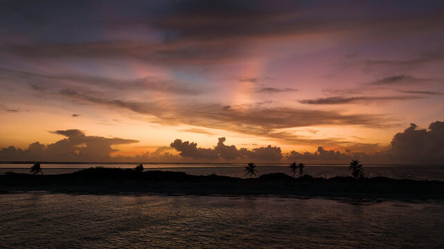 Aerial view of a serene tropical island at sunrise with palm trees and tranquil sea, Bonaire, Caribbean Netherlands.