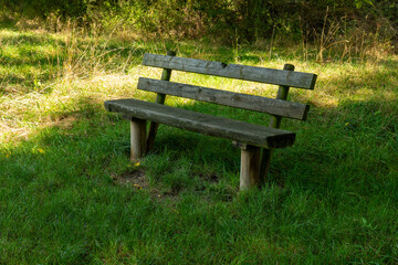 wooden bench is sitting in a grassy field