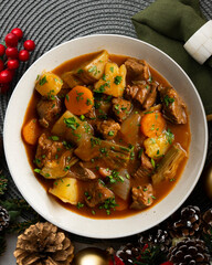 Beef stew with potatoes and artichoke. Top view table with Christmas decoration.