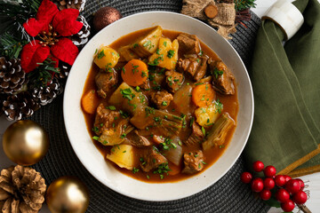 Beef stew with potatoes and artichoke. Top view table with Christmas decoration.