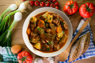 Beef stew with potatoes and artichoke. Top view table with  decoration.