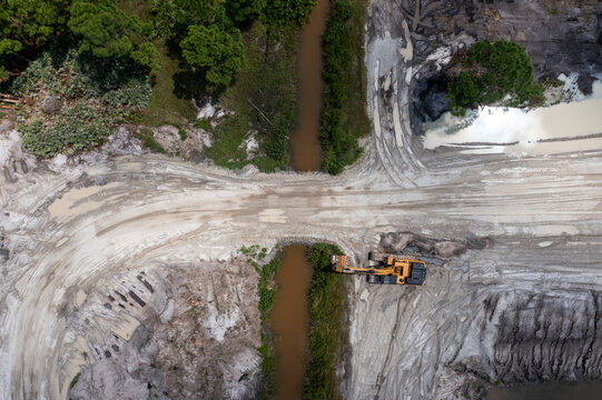 Aerial view of Stavola Aggregate Supply construction site with excavators and machinery surrounded by trees and a river, Fellsmere, United States.