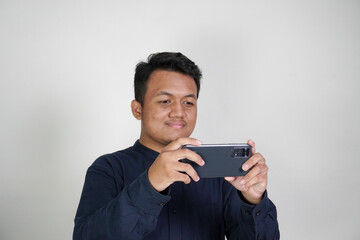 Southeast Asian man wearing navy blue shirt watching on his mobile phone