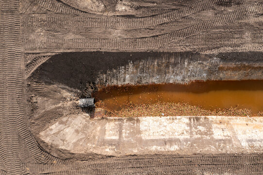 Aerial view of drainage canal with brown water and surrounding soil patterns, Fellsmere, Florida.