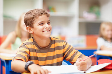 Writing, happy and child in class with books for learning, education and lesson for development. Primary school, academy and boy with stationery for test, creativity and assignment for knowledge