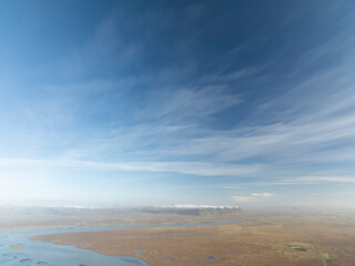 Aerial view of serene and expansive landscape under a clear blue sky with beautiful clouds, Olfus, Iceland.