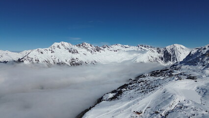 Obraz premium Lovely shot of the French Alps near Vaujany, France. A sea of mist down in the valley can be seen in the picture during this lovely and sunny day in the heights of the ski station