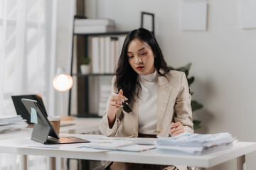 Focused & Determined: A young businesswoman meticulously reviewing documents at her desk,...