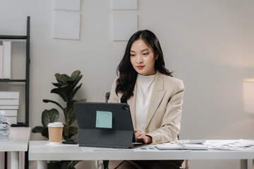 Focused and Determined:  A young Asian businesswoman is diligently working at her laptop in a...