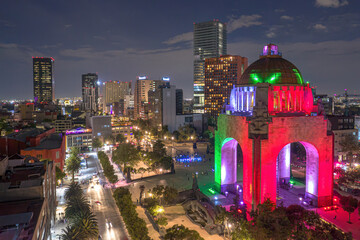 Aerial view of the illuminated revolution monument amidst a vibrant cityscape at night, Cuauhtemoc, Mexico.