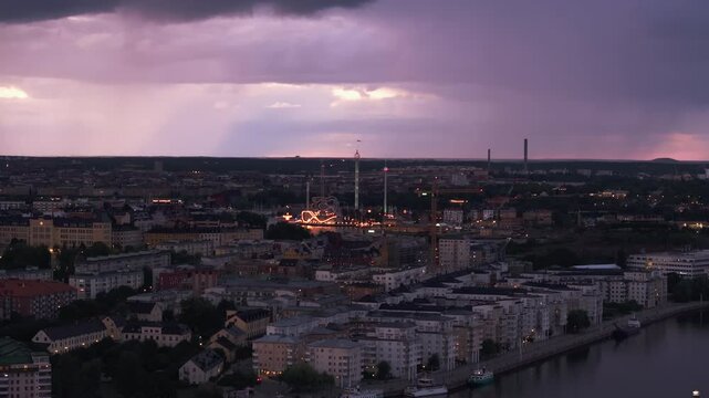 Aerial view of Stockholm, featuring Grona Lund amusement park as the sun sets and the city lights begin to shine. Purple clouds fill the sky