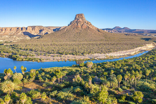 Aerial view of pilon hill with river and rugged vegetation in a serene desert landscape, Comondu Municipality, Mexico.
