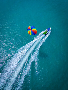 Aerial view of parasailing over the beautiful ocean with boats at Pantai Cenang, Kampung Lubok Buaya, Malaysia.