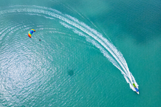 Aerial view of parasailing and boats over the beautiful ocean at Pantai Cenang, Kampung Lubok Buaya, Malaysia.