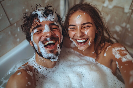 A man and woman are in a bathtub, both smiling and laughing