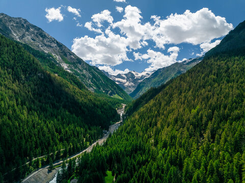 Aerial view of lush green mountains and tranquil valley with a winding road in Gran Paradiso National Park, Cogne, Italy.