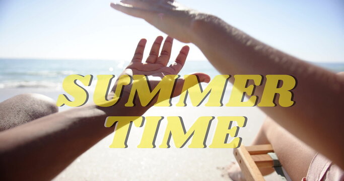 Image of summer time text over diverse couple spending time on beach
