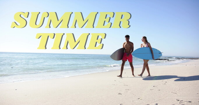 Image of summer time text over diverse couple walking with surfboards on beach