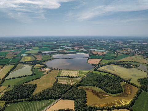 Aerial view of beautiful fields and a tranquil lake surrounded by trees in Parc des Oiseaux, Saint-Paul-de-Varax, France.