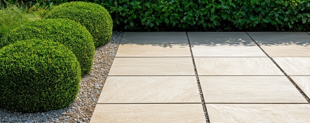 Obraz premium A serene outdoor scene featuring elegant stone tiles bordered by manicured bushes and gravel, perfect for landscaping concepts.