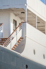 Staircase Of A Classic Ship, With The Black And White Hull Detail, The Wooden Staircase Leads To The Upper Deck. The Clear Blue Sky Provides A Clean, Uncluttered Background.