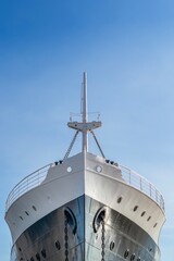 Front View Of The Bow Of An Antique Ship, With The Black And White Hull In Detail, With Anchor Chains And Portholes. The Clear Blue Sky Provides A Clean, Uncluttered Background.
