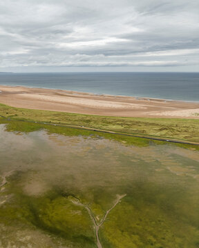 Aerial view of serene Holy Island at low tide with tranquil coastline and wetlands, Berwick-upon-Tweed, United Kingdom.