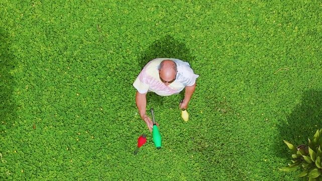 A juggler seen from top down aerial view practicing on a grassy lawn