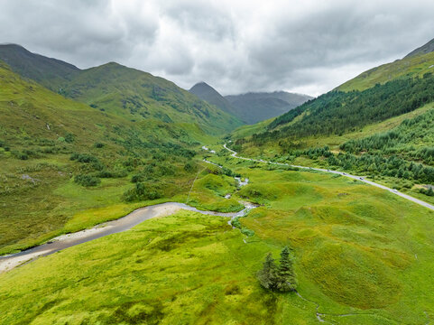 Aerial view of winding river through lush green valley and majestic mountains, Kyle, United Kingdom.