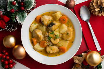 Hake stew with potatoes and carrots. Top view table with Christmas decorations.